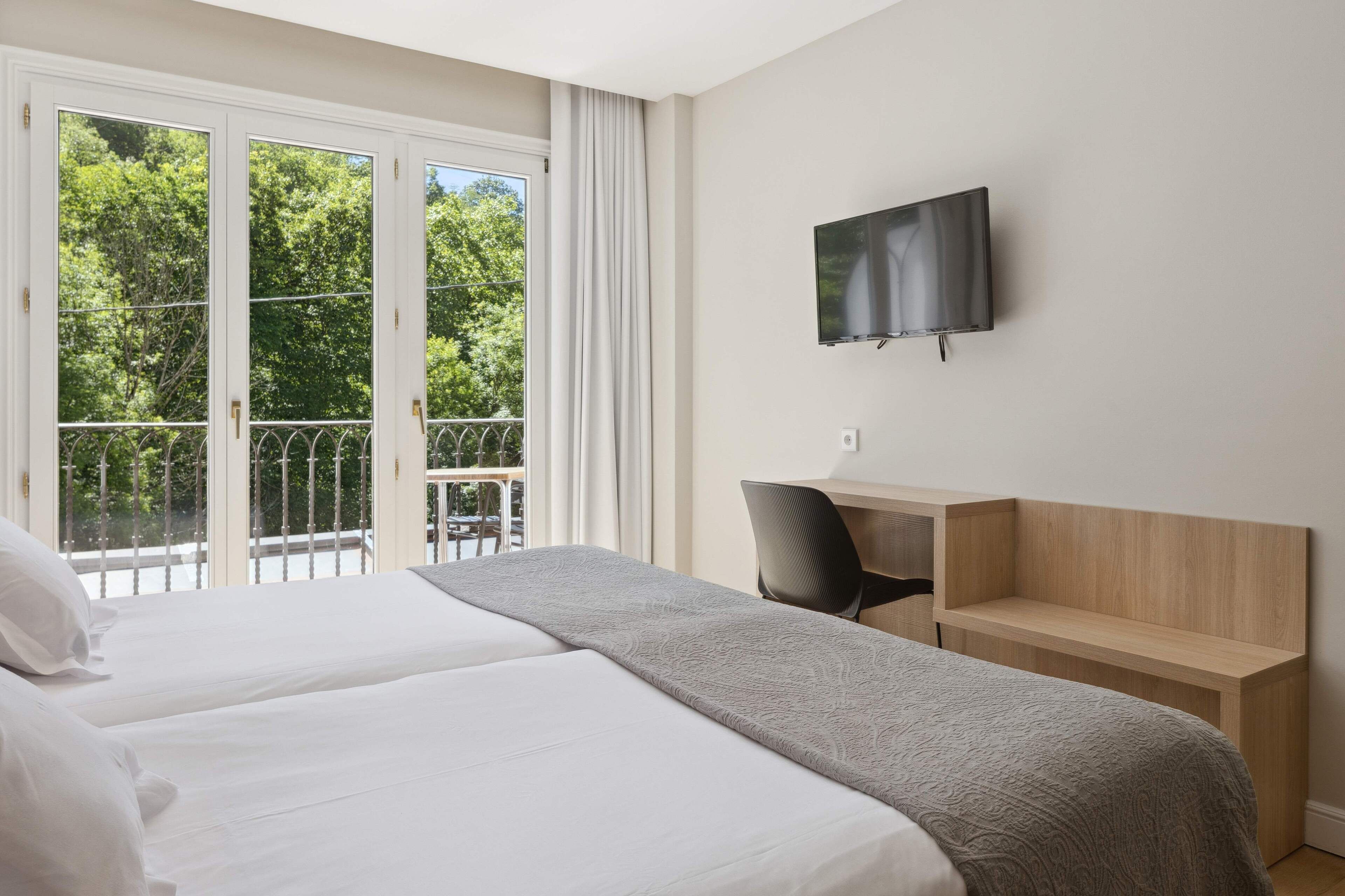 Une chambre d’hôtel avec un grand lit, un bureau et un téléviseur fixé au mur.