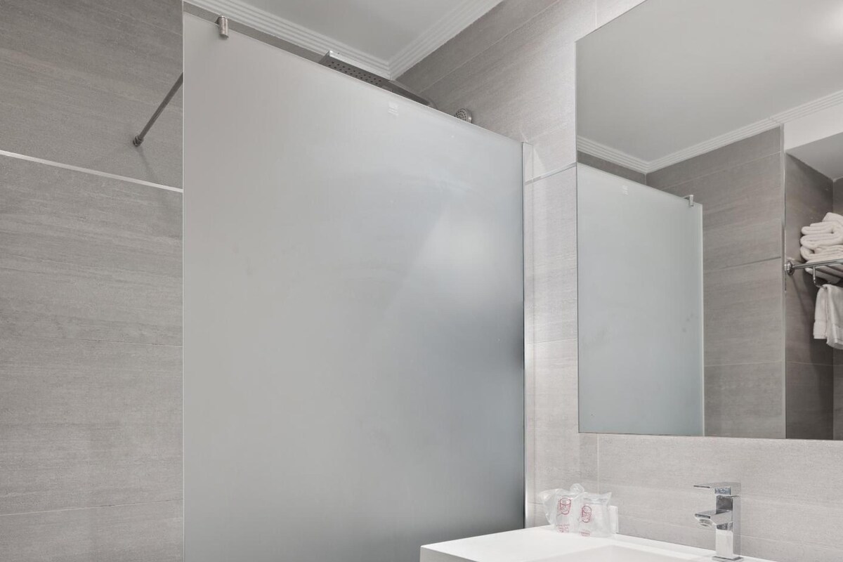 A modern bathroom with a shower, a sink, and a mirror.