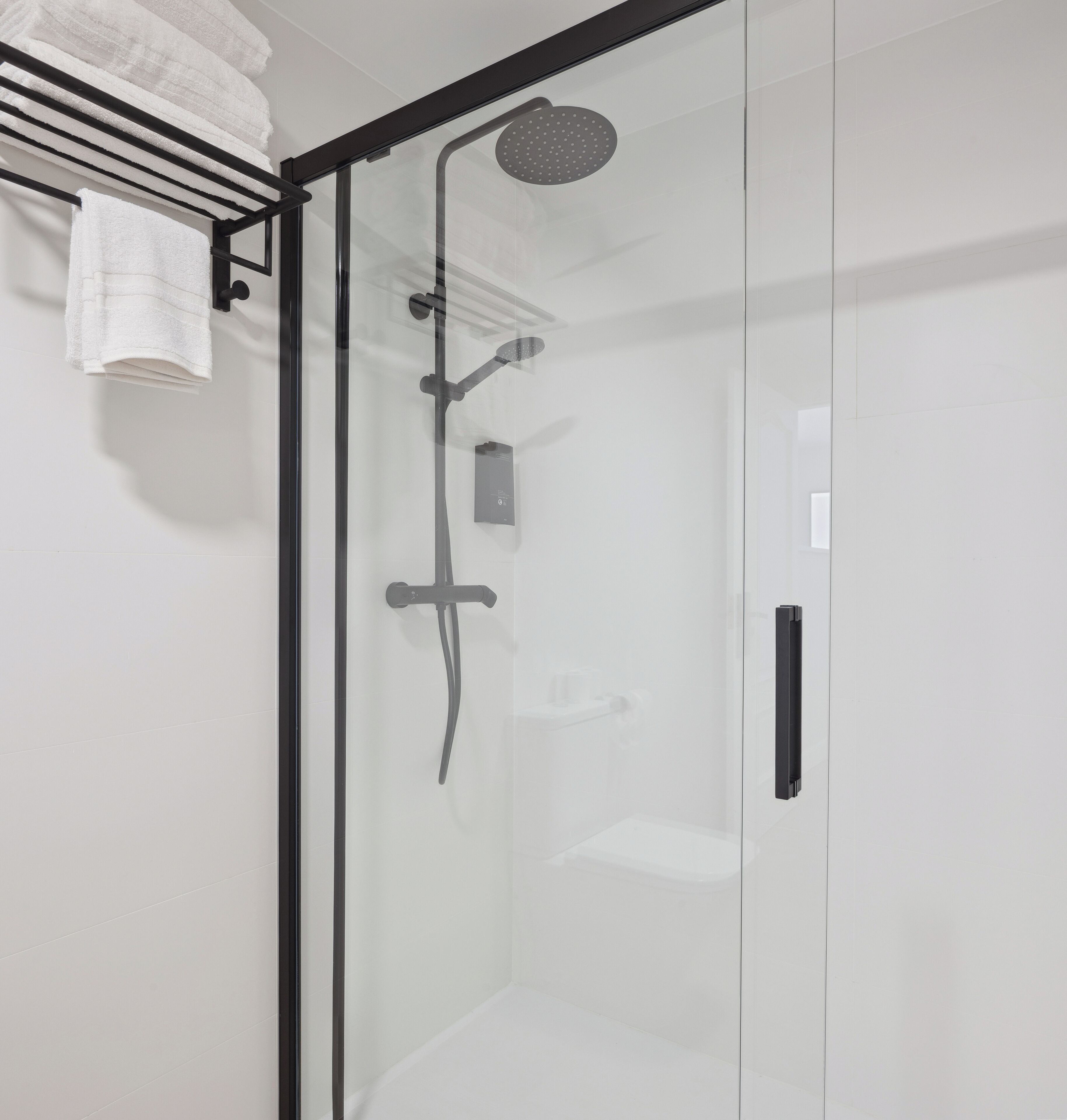 A modern shower with a glass door, a towel rack, and a control panel.