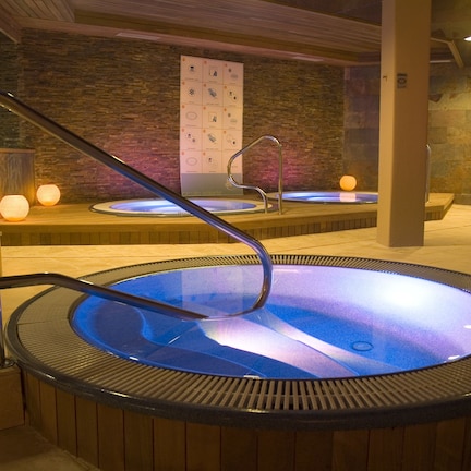 A spa area with two hot tubs, wooden benches, and a stone wall with a poster.