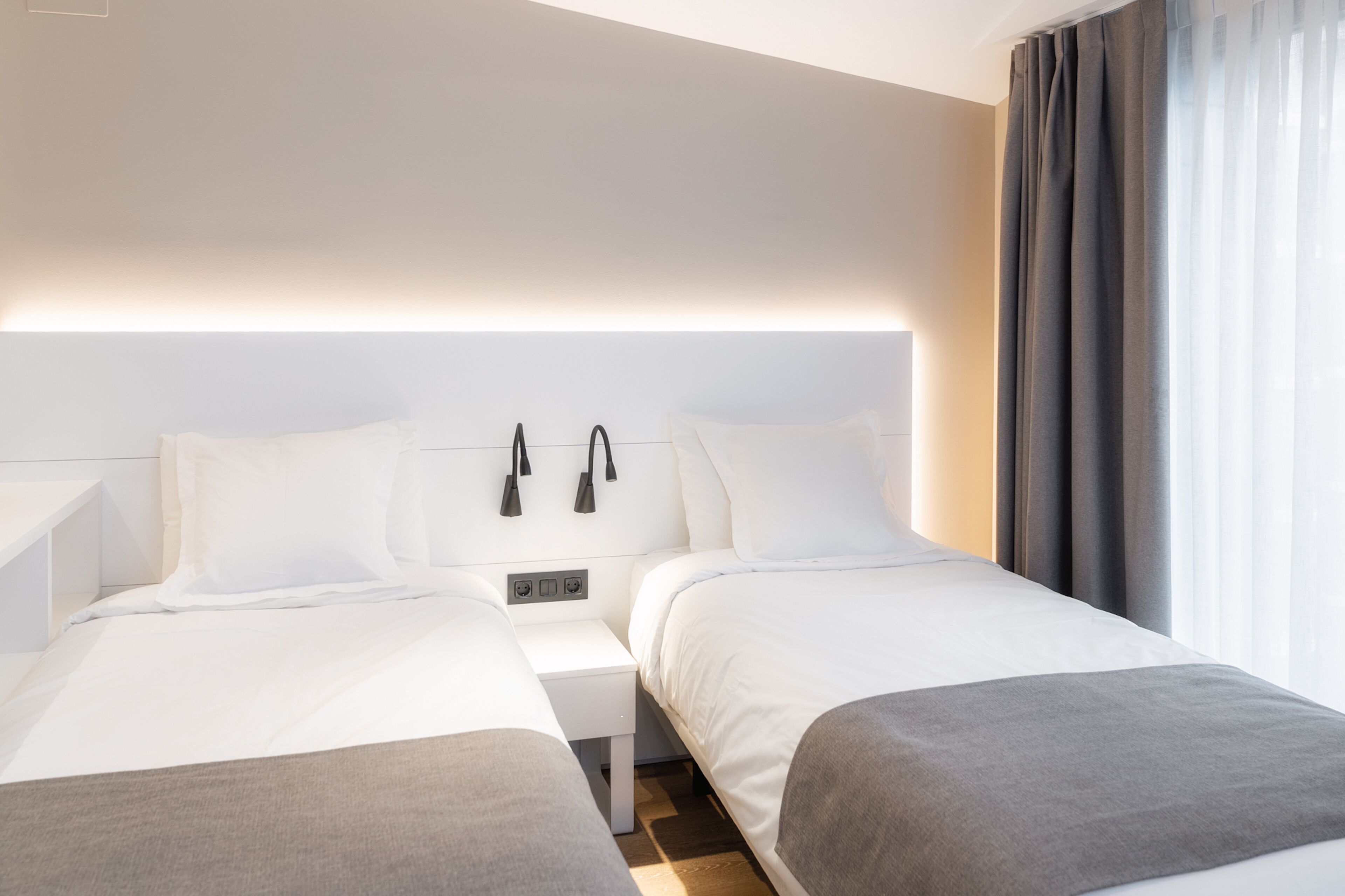 Ein modernes Hotelzimmer mit zwei Betten, einem Nachttisch und einem Beistelltisch.