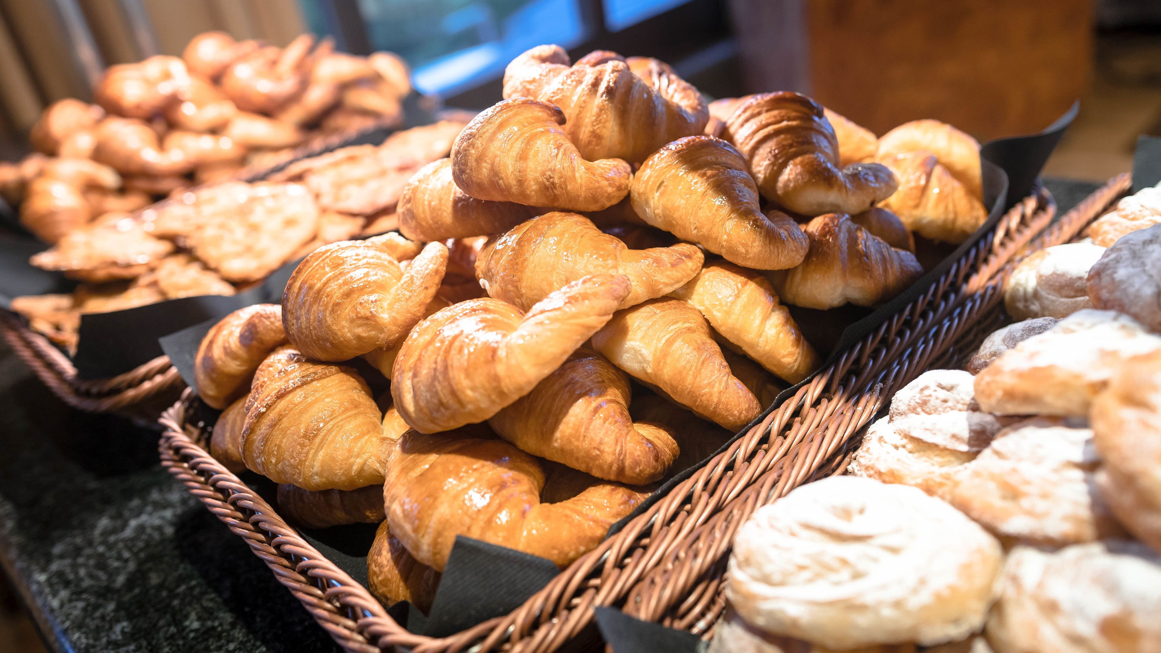 A display of various baked goods, including croissants and other pastries, arranged in baskets.