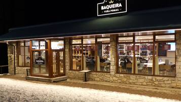 Un bar de vinos con fachada de piedra y amplios ventanales.