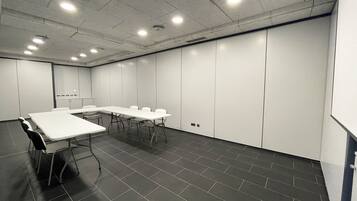 A conference room with a long table, chairs, and a whiteboard.