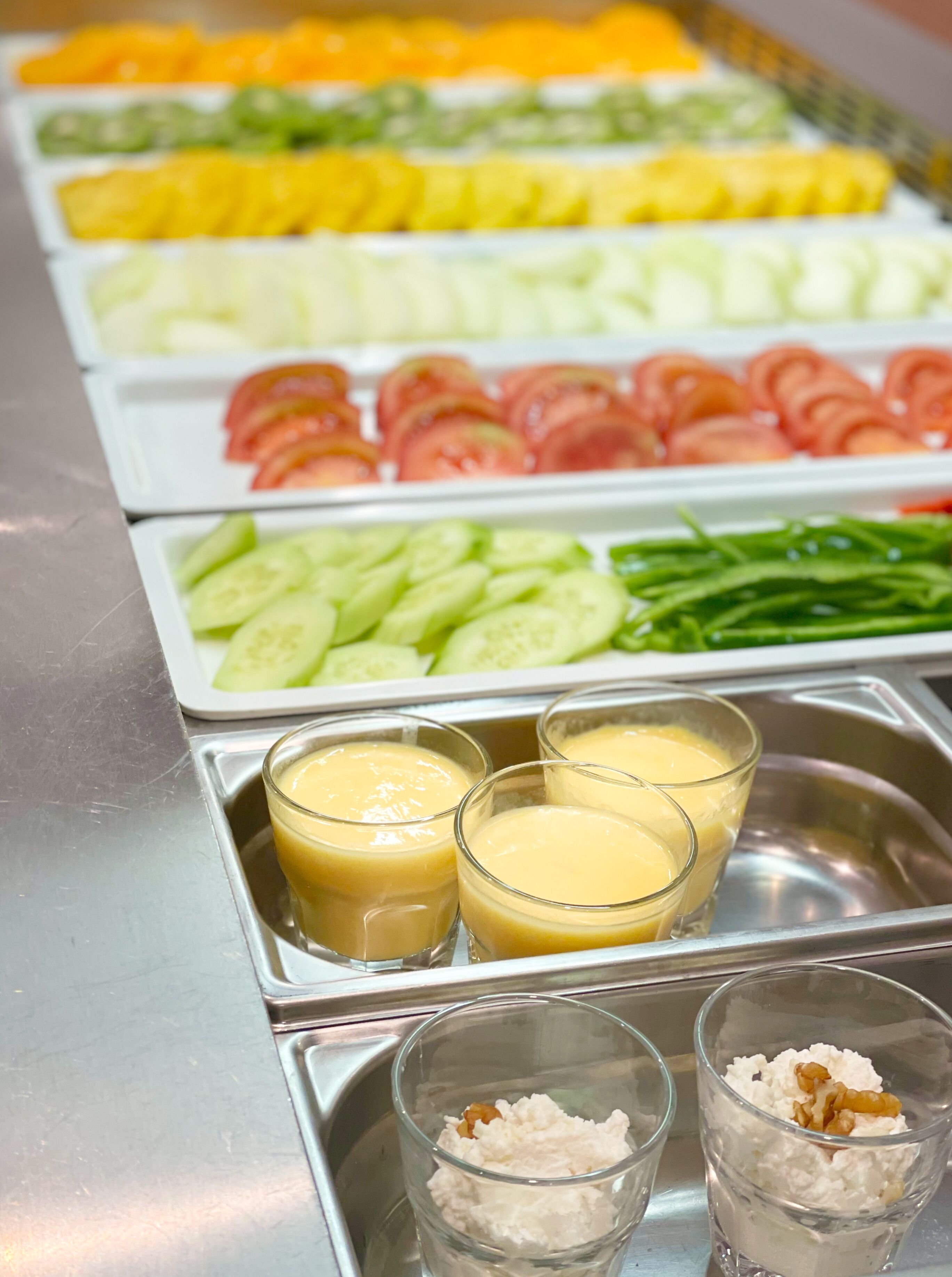 A buffet with various food options including sliced fruits, vegetables, and creamy dishes.