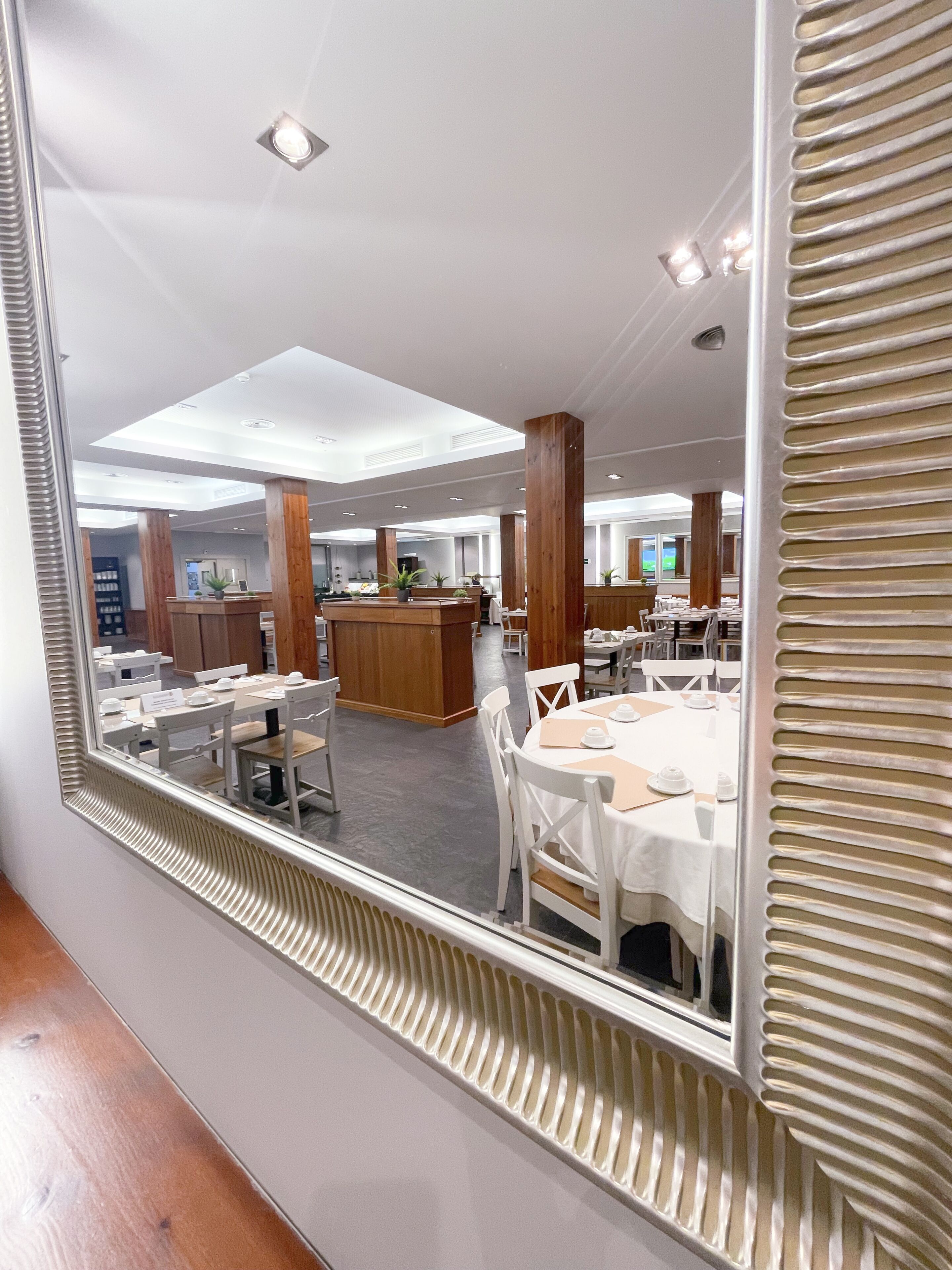 Un restaurante con mesas y sillas blancas, un mostrador de recepción de madera y vistas al salón comedor.
