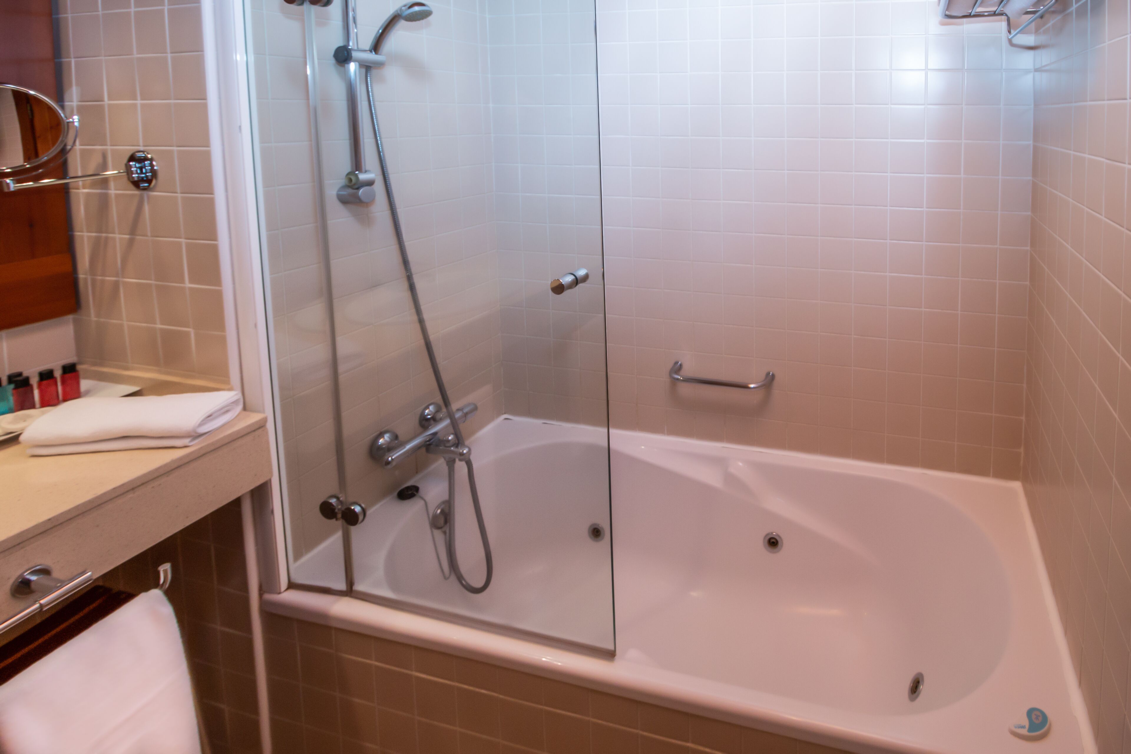 Un baño moderno con ducha envuelta en vidrio, una bañera blanca y un lavamanos con espejo y toalla.