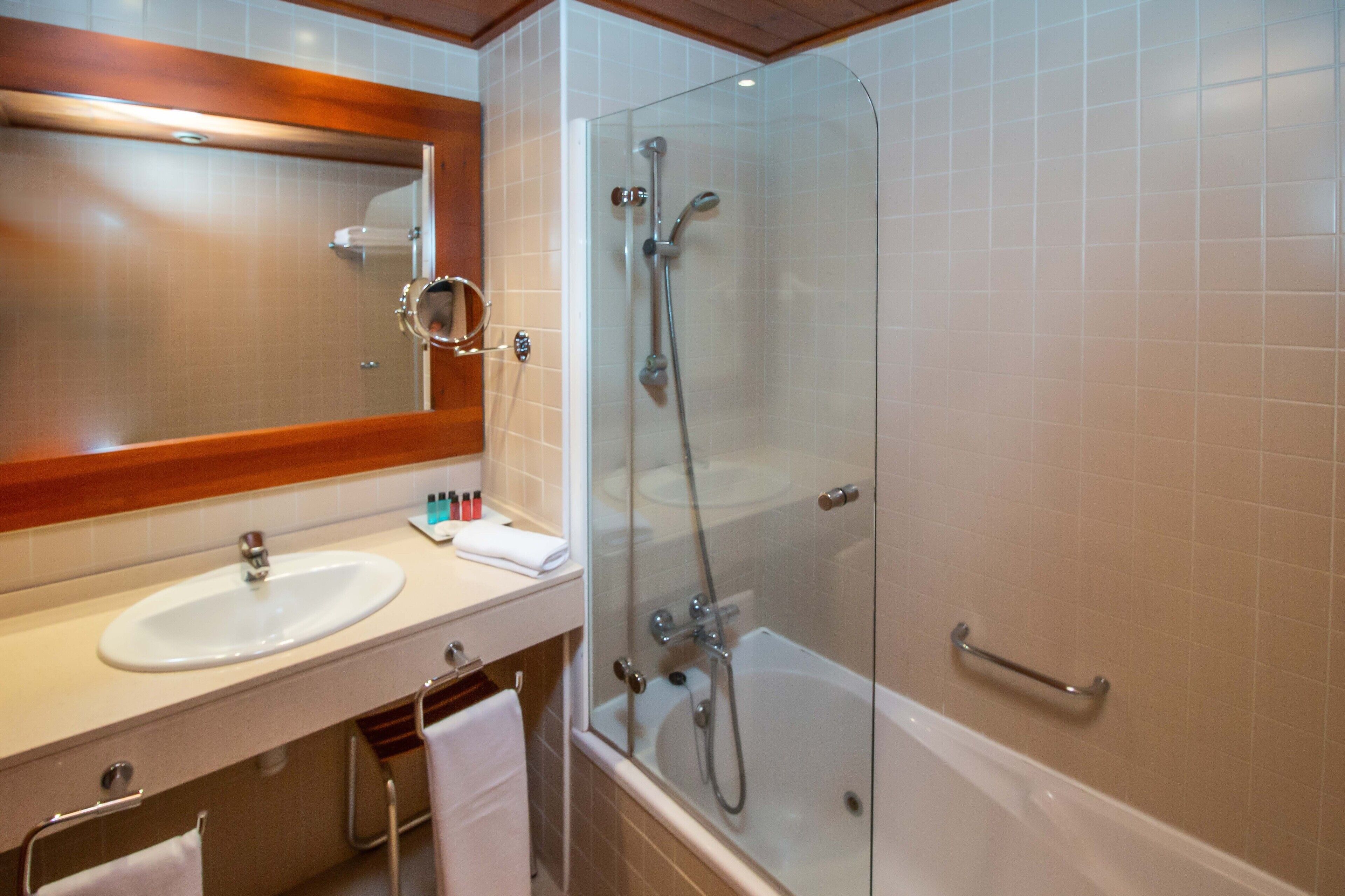A bathroom with a sink, mirror, and shower.