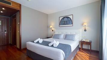 Habitación de hotel con una cama grande, dos lámparas de noche, un cuadro en la pared y suelo de madera.