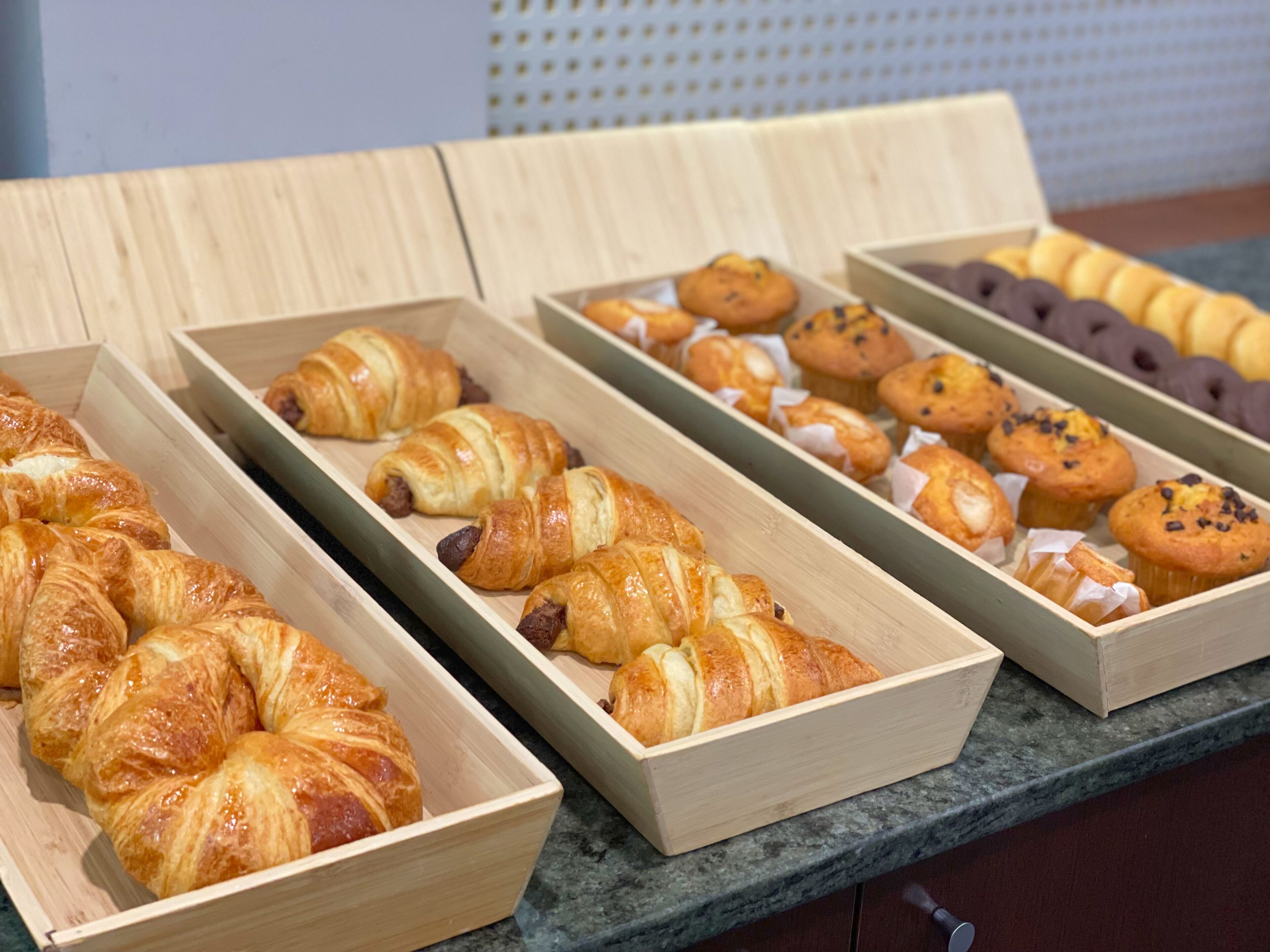 A variety of baked goods displayed in wooden boxes on a countertop.