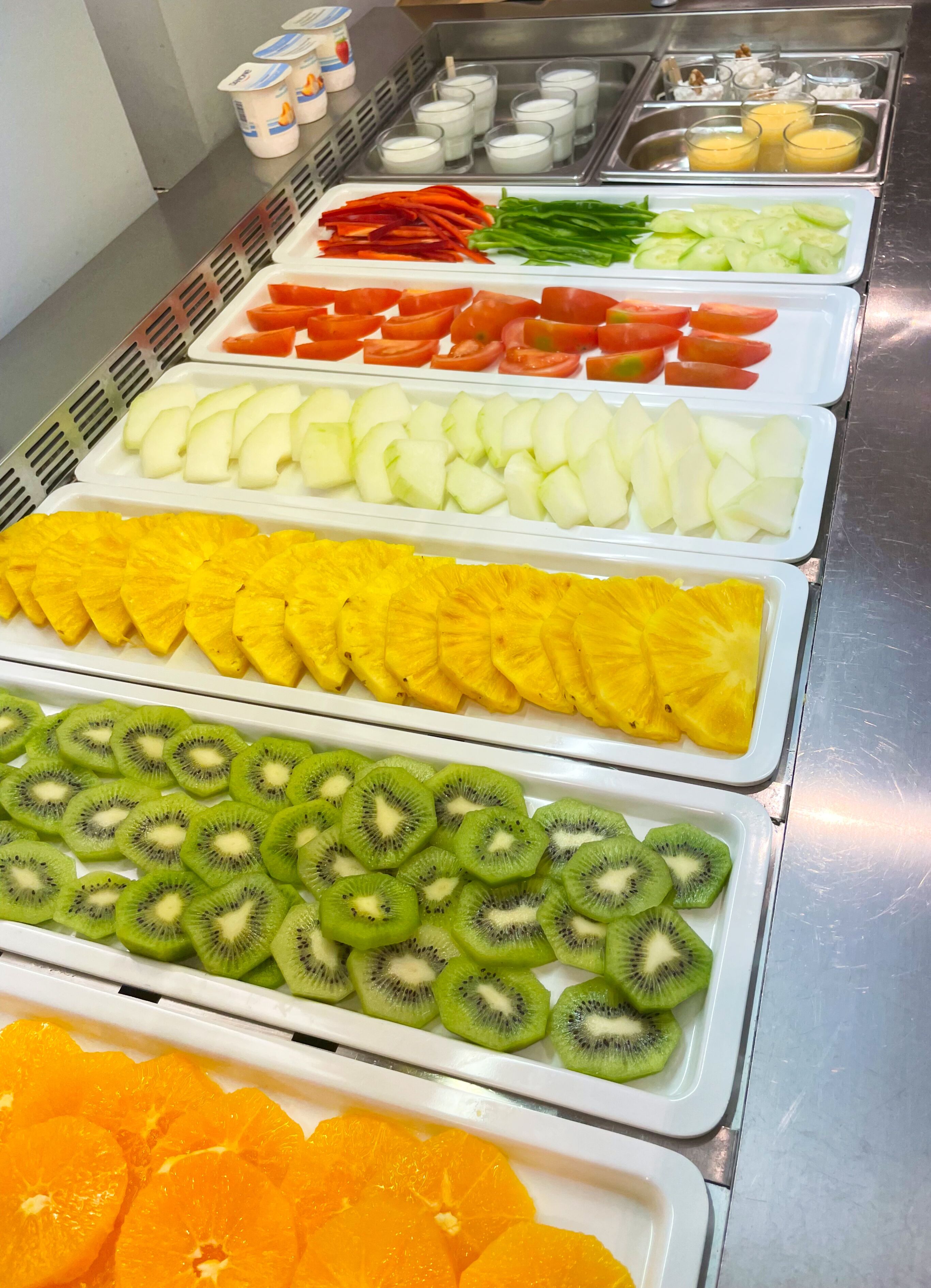Um buffet com diversas frutas e legumes dispostos em bandejas.