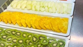 Um buffet com diversas frutas e legumes dispostos em bandejas.