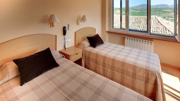 Habitació d'hotel amb dos llits, una taula de nit, una làmpada, un telèfon i una finestra que ofereix vistes a la zona rural.