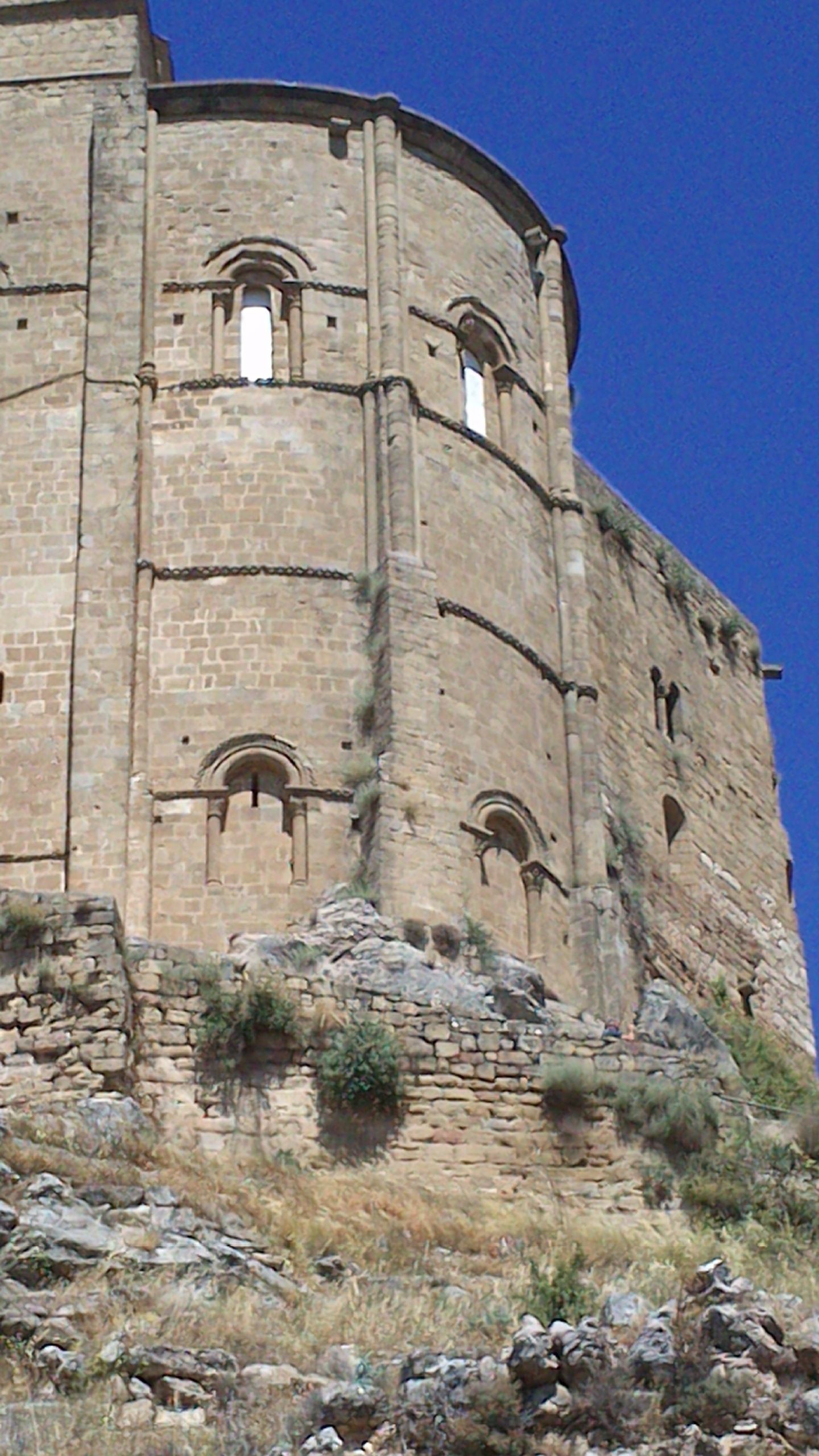 Un edificio grande y antiguo de piedra con ventanas de arco y una torre circular.
