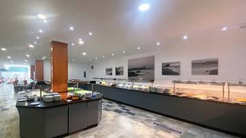 A buffet area with a marble floor and a long counter displaying various food items.