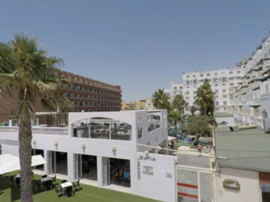 A hotel with multiple floors, outdoor seating areas, and a pool.