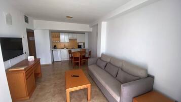 A living room with a sofa, a coffee table, and a TV on a wooden cabinet.