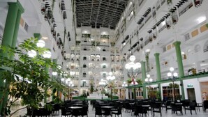 A multi-level atrium with a high ceiling, multiple floors, and a central open space with tables and chairs.