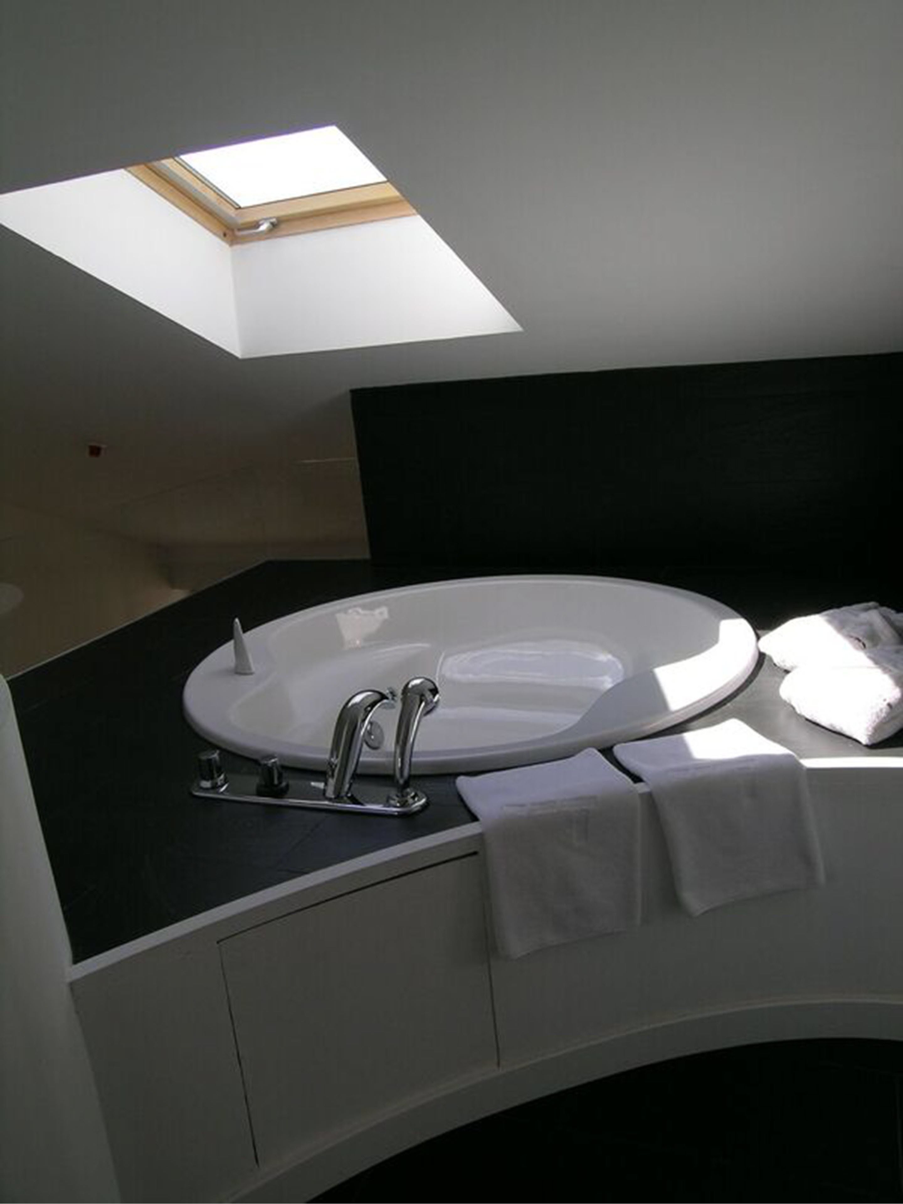 A modern bathroom with a skylight above the sink, a black countertop, and a white vanity.