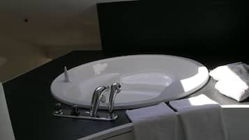 A modern bathroom with a skylight above the sink, a black countertop, and a white vanity.