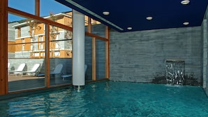 An indoor swimming pool with clear glass walls, a blue ceiling, and a water feature. - Tierra De Biescas Hotel (Biescas)