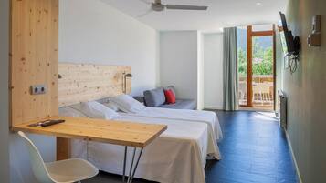 Een moderne hotelkamer met twee bedden, een houten bureau, een witte stoel en een plafondventilator.