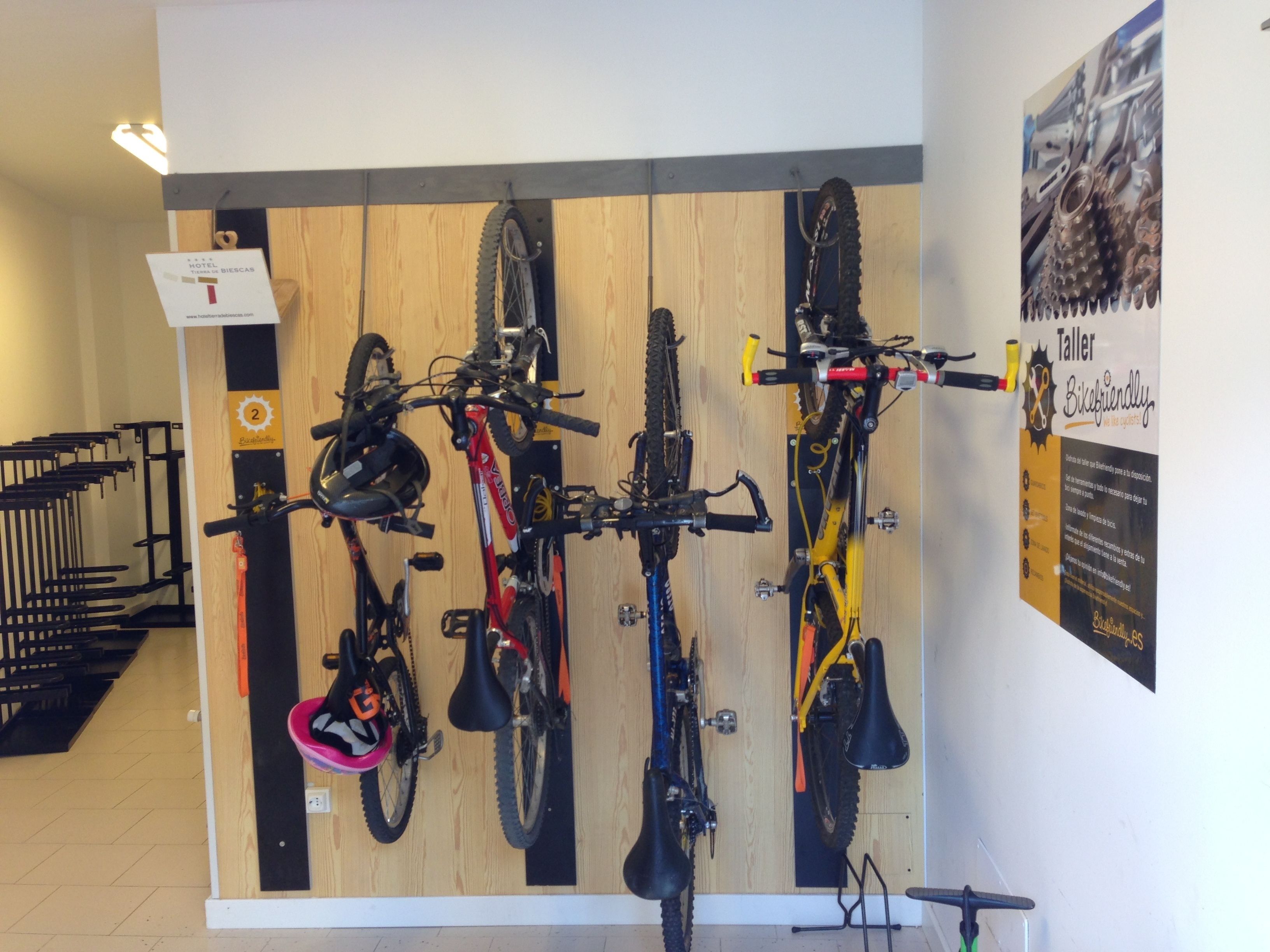 Un soporte para bicicletas en la pared con varias bicicletas, un panel de pared de madera y un cartel que indica la habitación número 2.