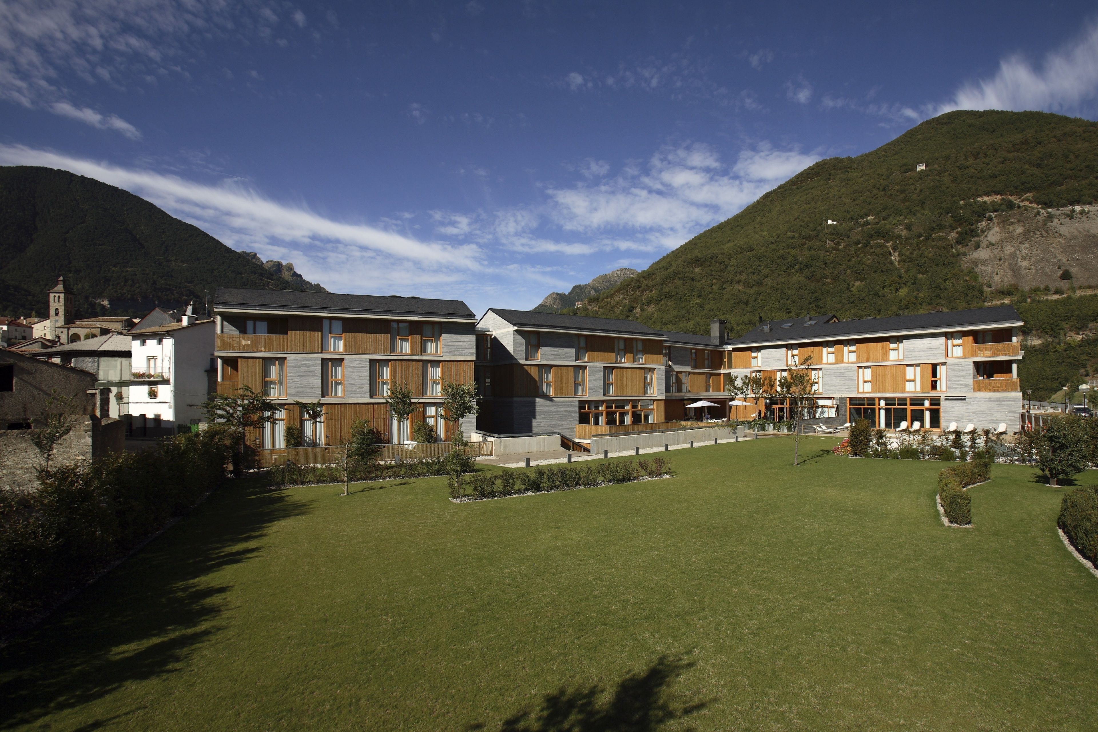 A modern hotel with multiple floors, a central courtyard, and a mountain backdrop.
