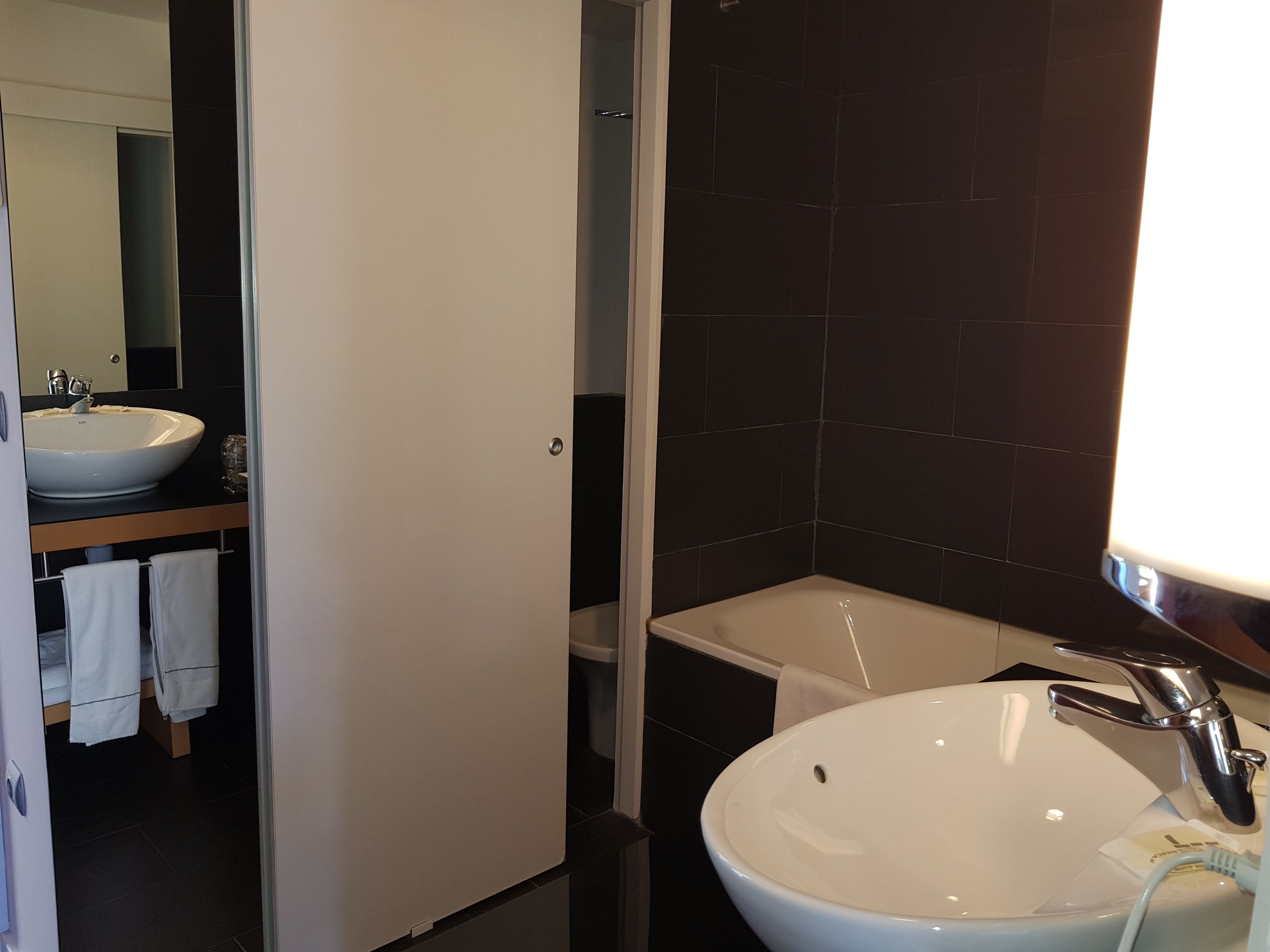 Een moderne badkamer met een wit wastafelmeubel, een spiegel en een bad.