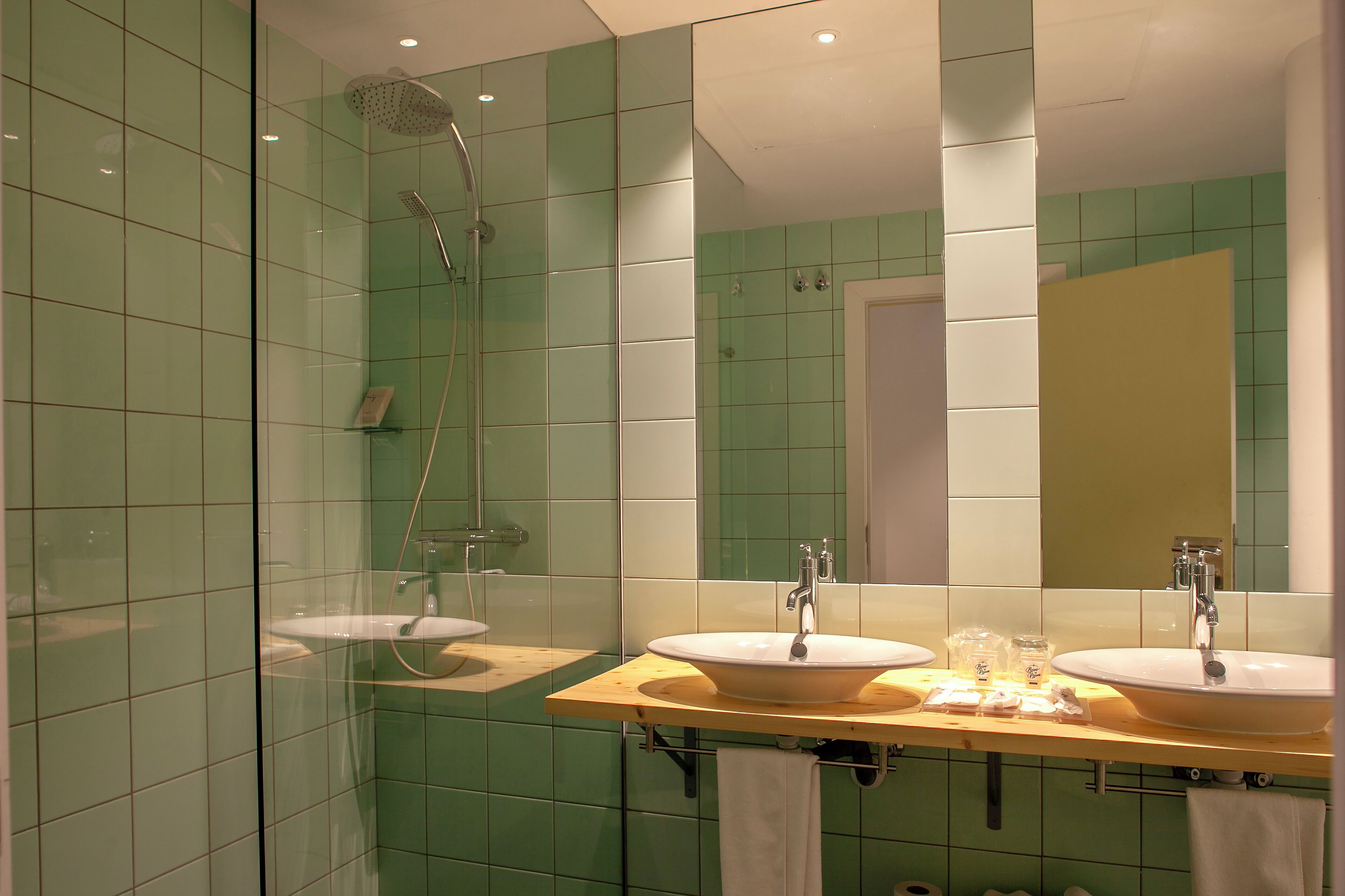 Un baño con dos lavamanos, una ducha y un espejo.
