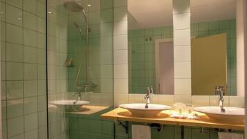 Un baño con dos lavamanos, una ducha y un espejo.