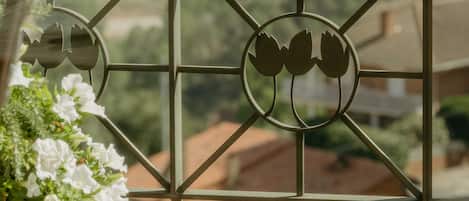 A balcony with a metal railing, a flower pot with white flowers, and a view of houses in the background.
