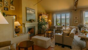 Una sala de estar acogedora con chimenea, asientos cómodos, un comedor y grandes ventanales con vistas.