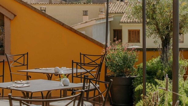 Une terrasse avec des tables et des chaises, une vue sur un château historique et un lampadaire.