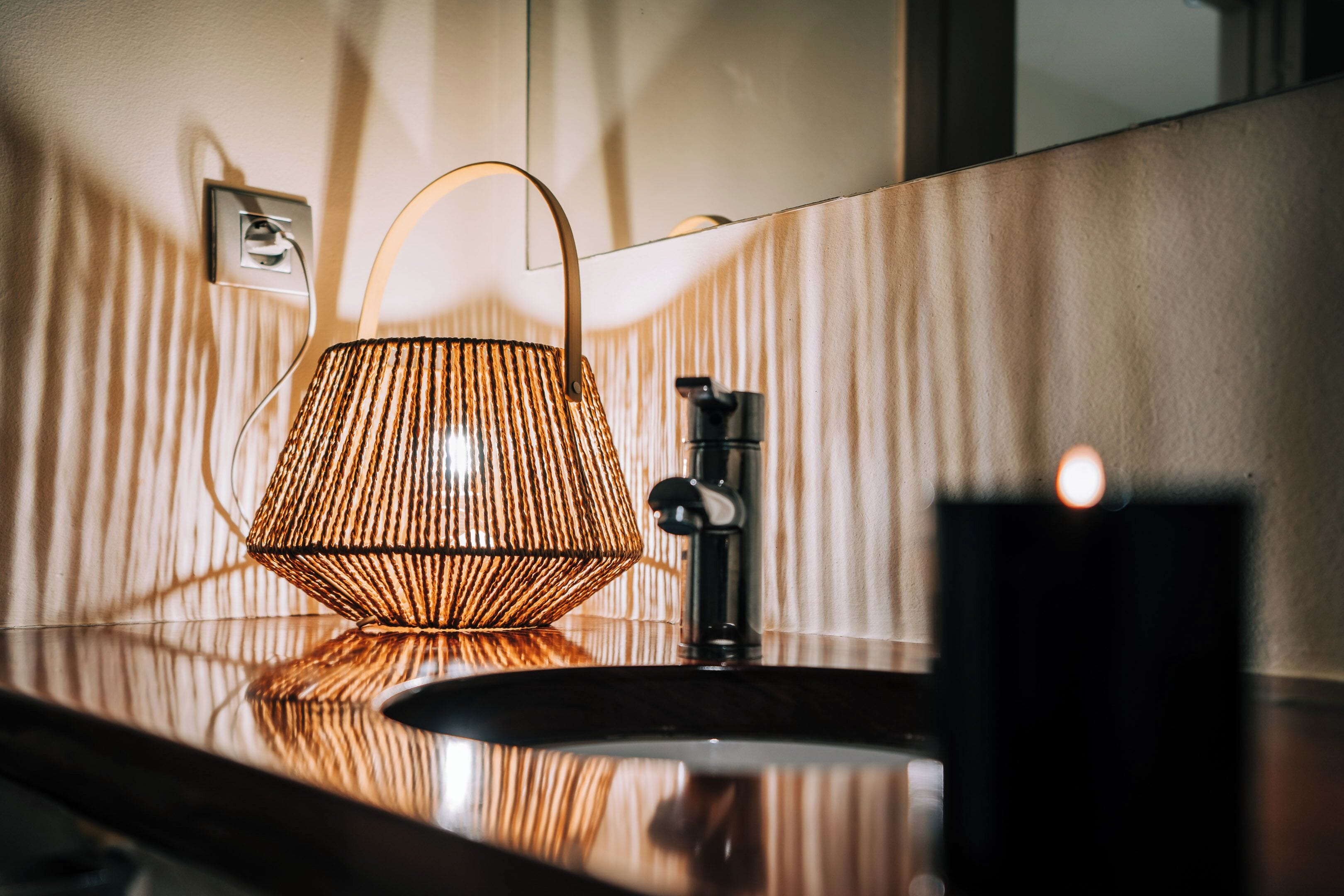 A bathroom with a modern sink, a hanging light fixture, and a mirror.