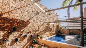 A stone-walled outdoor area with a pool, seating, and potted plants. - Gran Claustre Boutique Hotel & SPA (Altafulla)