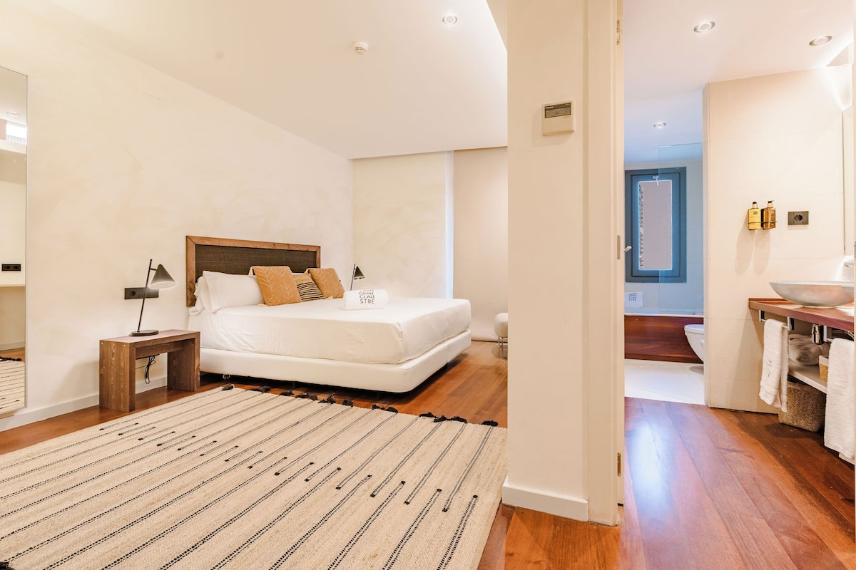 Une chambre moderne avec un grand lit, une table de chevet, une commode et un plancher en bois.