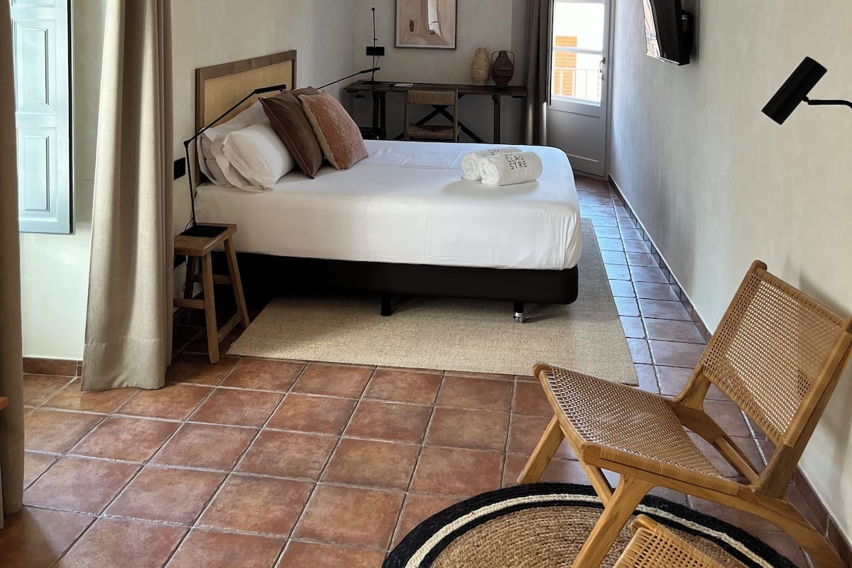 Une chambre d’hôtel avec un lit, une chaise, un bureau et un téléviseur.
