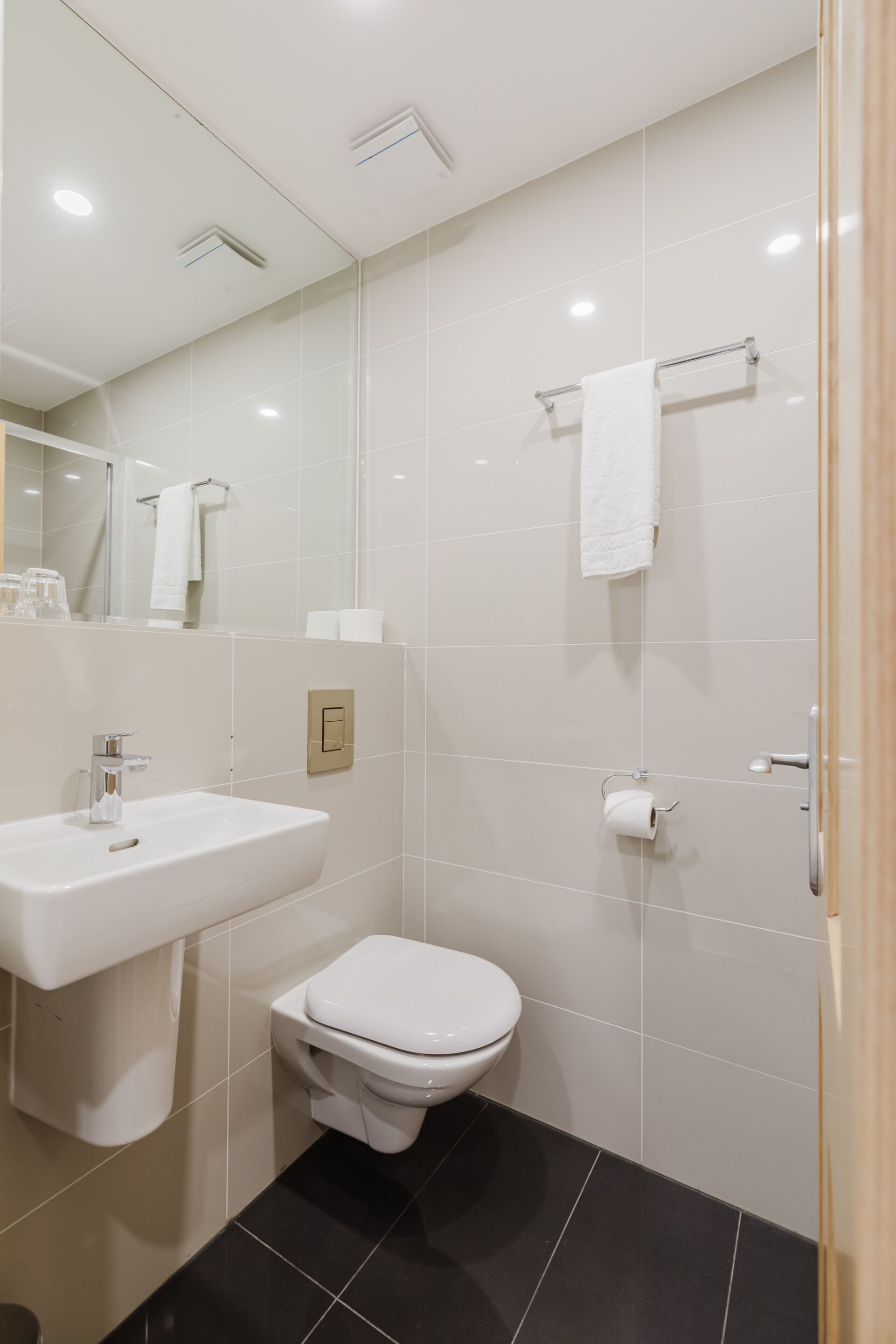 A modern bathroom with a white sink, toilet, and mirror.