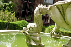 A stone fountain with a dragon sculpture and water spouting from its mouth. - Hotel Jan Brito (Bruges)