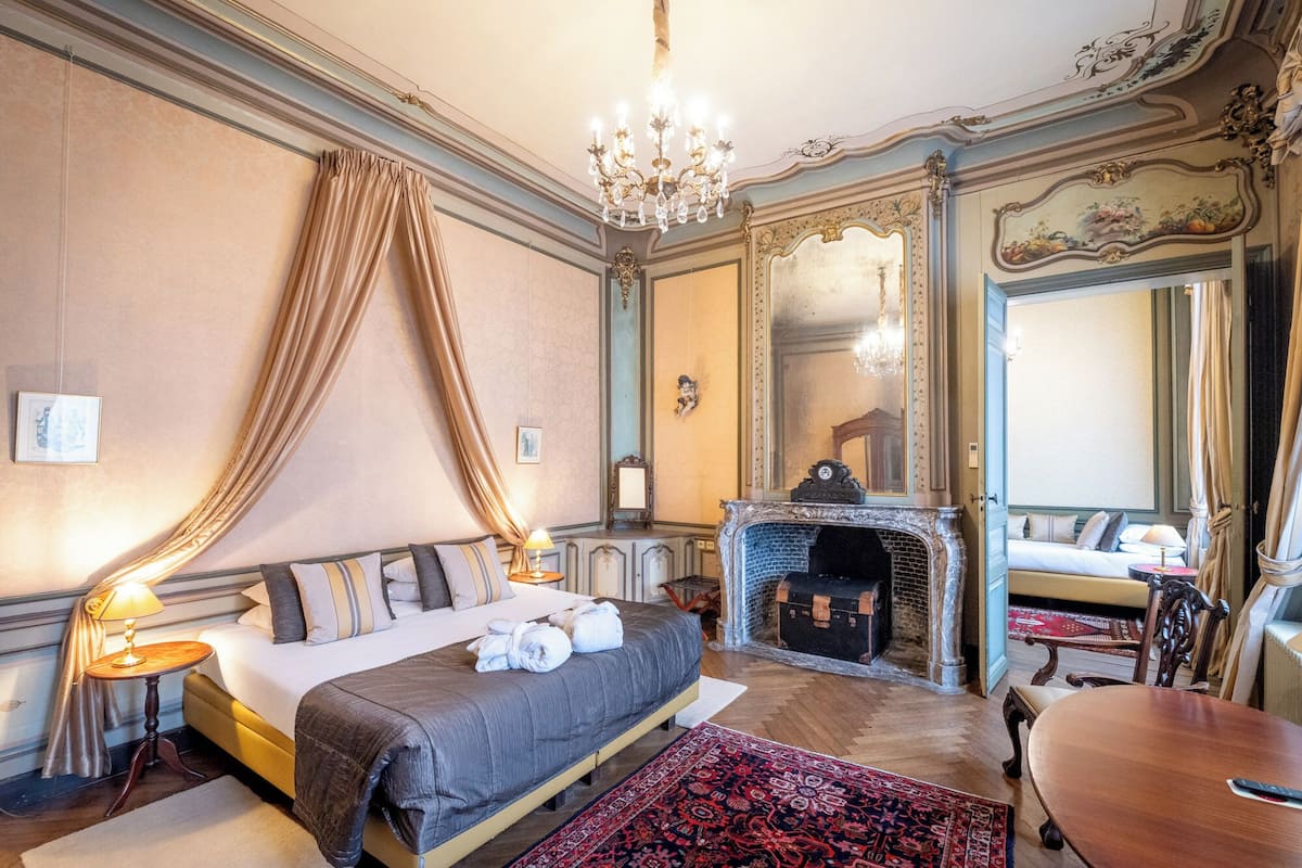 Un dormitorio lujoso con una cama grande, una chimenea y decoración ornamentada.