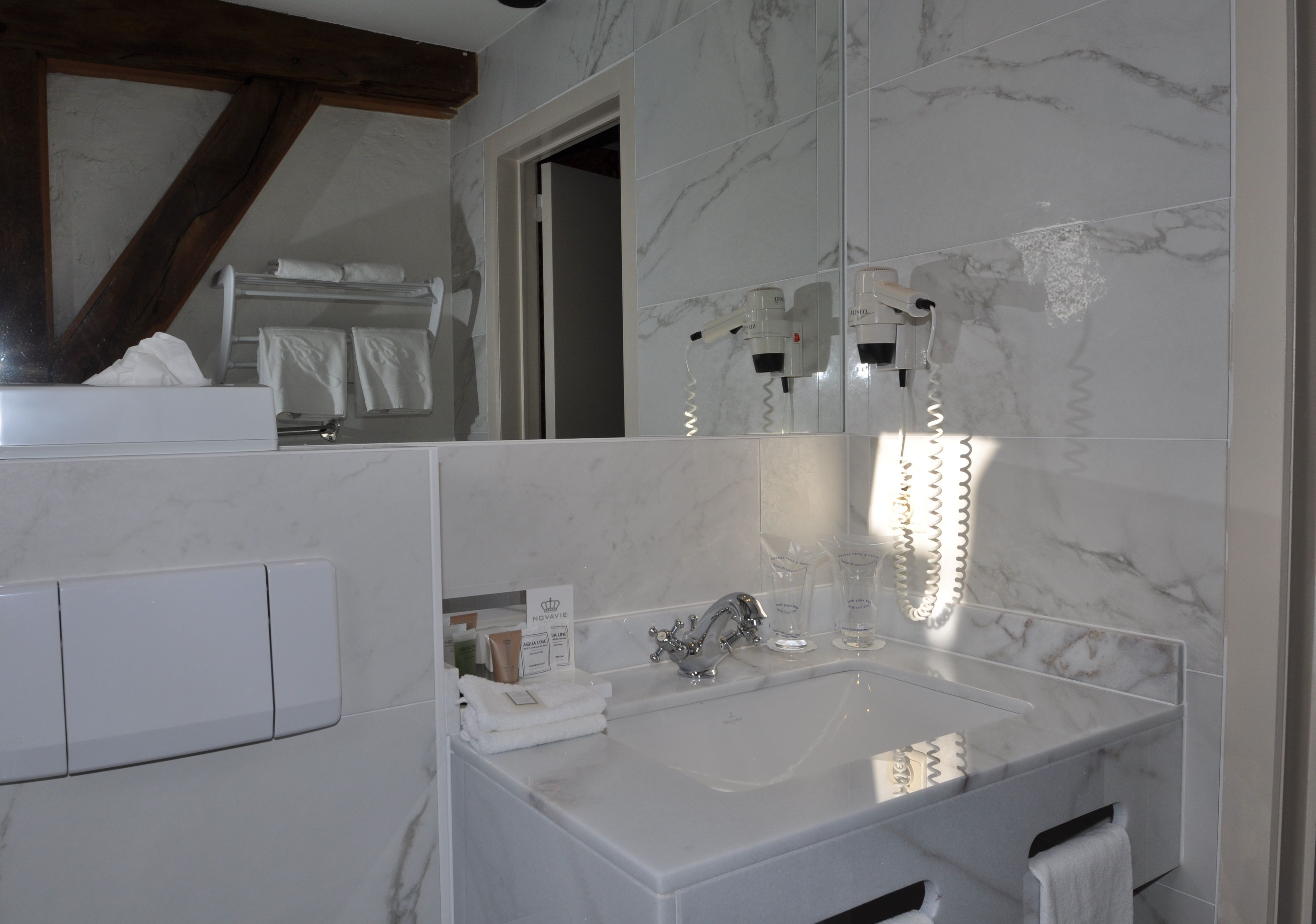 A bathroom with a marble sink, a towel rack, and a mirror.