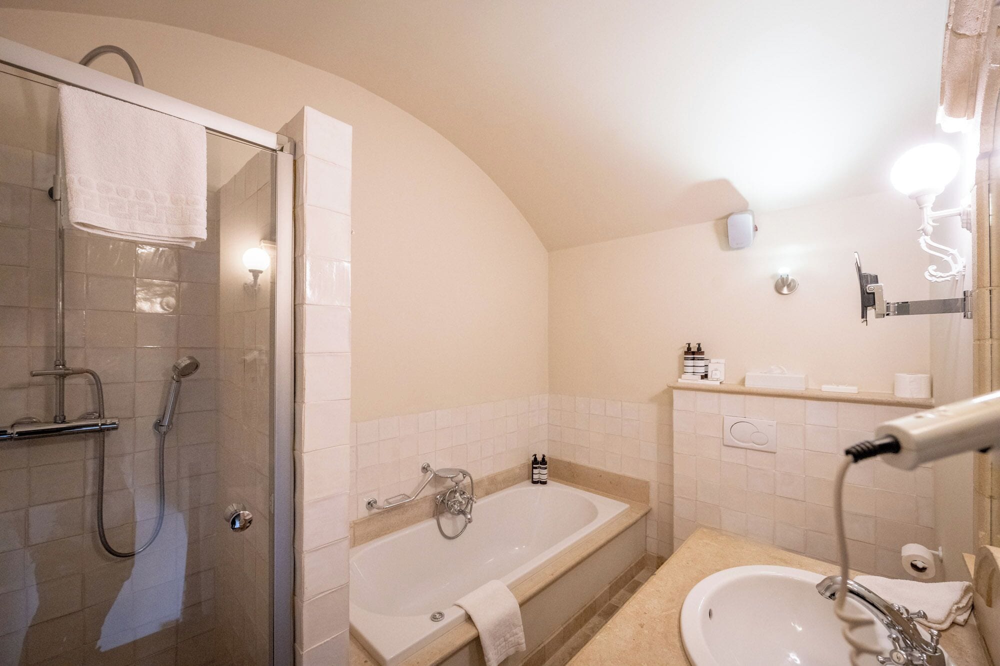A bathroom with a glass shower enclosure, a bathtub, and a sink.