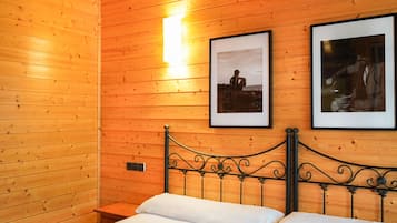 Una habitación de cabaña de madera con una cama, dos cuadros en la pared y una mesita de noche.