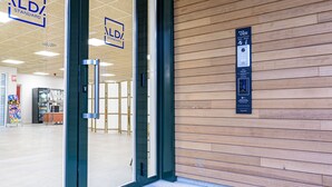 L’entrée d’un hôtel avec des portes en verre, un mur en bois et un lecteur de cartes d’accès numériques.