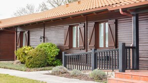 Un bâtiment en bois avec un toit recouvert de tuiles, des volets en bois et une rambarde en métal noir.