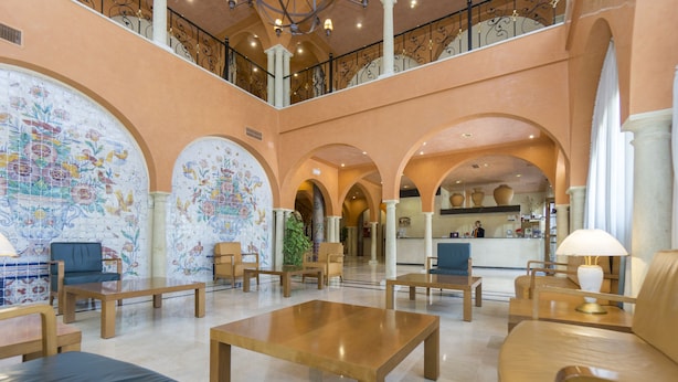 A spacious lobby with high ceilings, arched columns, and a central seating area with tables and chairs.