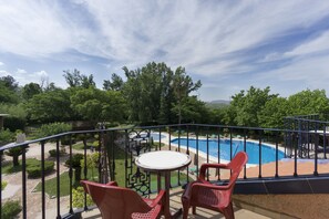 Un balcón con piscina, sillas rojas y una mesa.