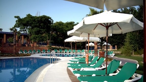 A poolside area with green lounge chairs and white umbrellas.