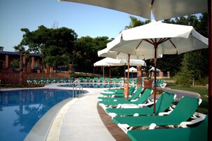 Una piscina al aire libre de temporada, sombrillas, tumbonas